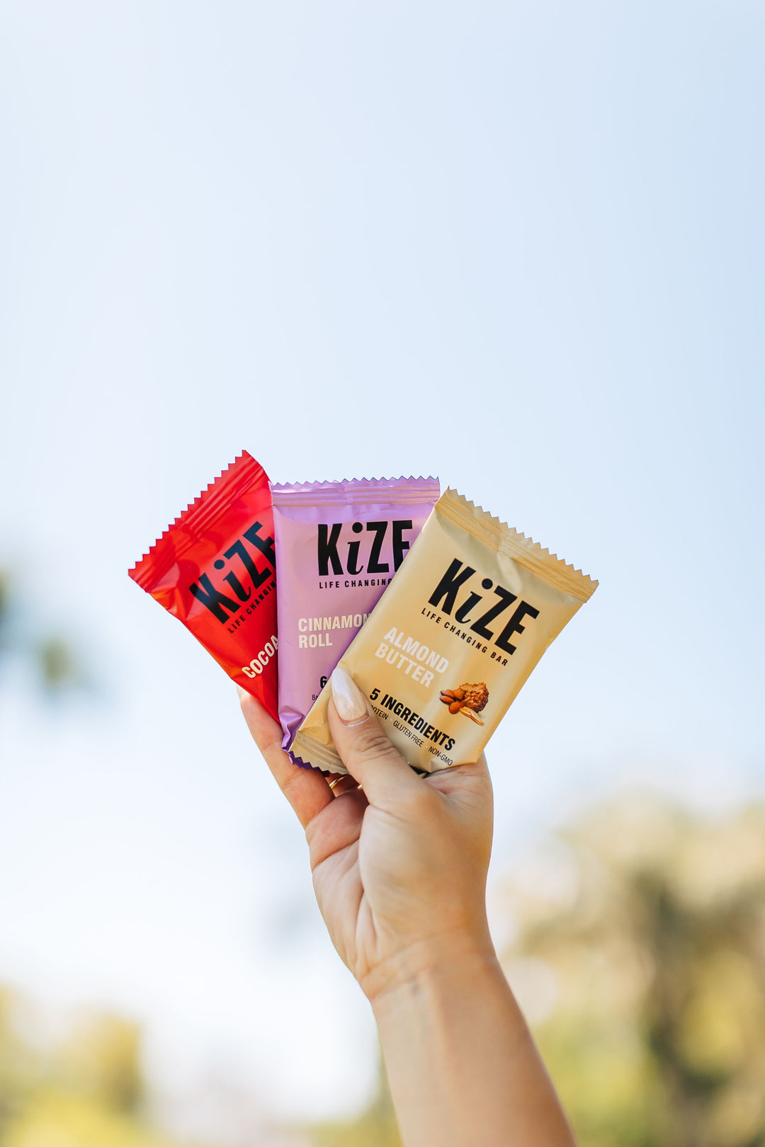 Hand holding 3 KiZE bars in the air.
