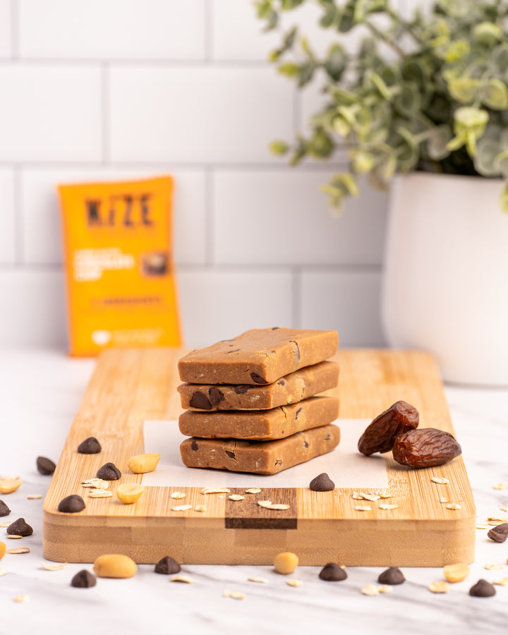 Peanut Butter Chocolate Chip Kize Protein Bar Stacked on Counter with Ingredients
