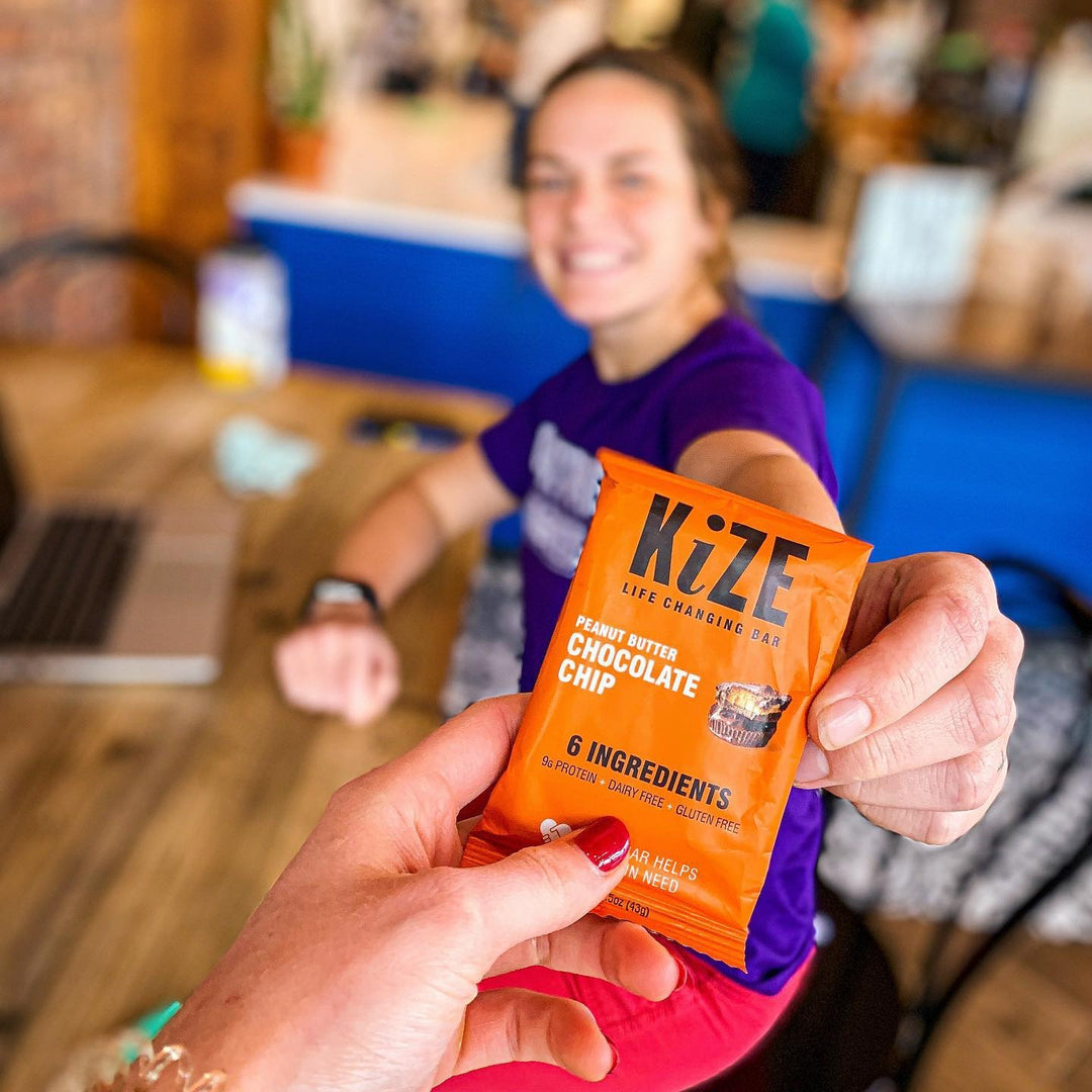 Women Holding Out Peanut Butter Chocolate Chip KiZE Bar