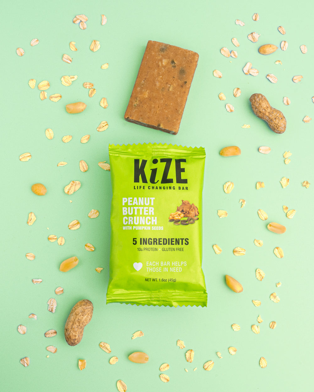 Peanut Butter Crunch with Pumpkin Seeds Kize Protein Bar Unwrapped Surrounded by Ingredients